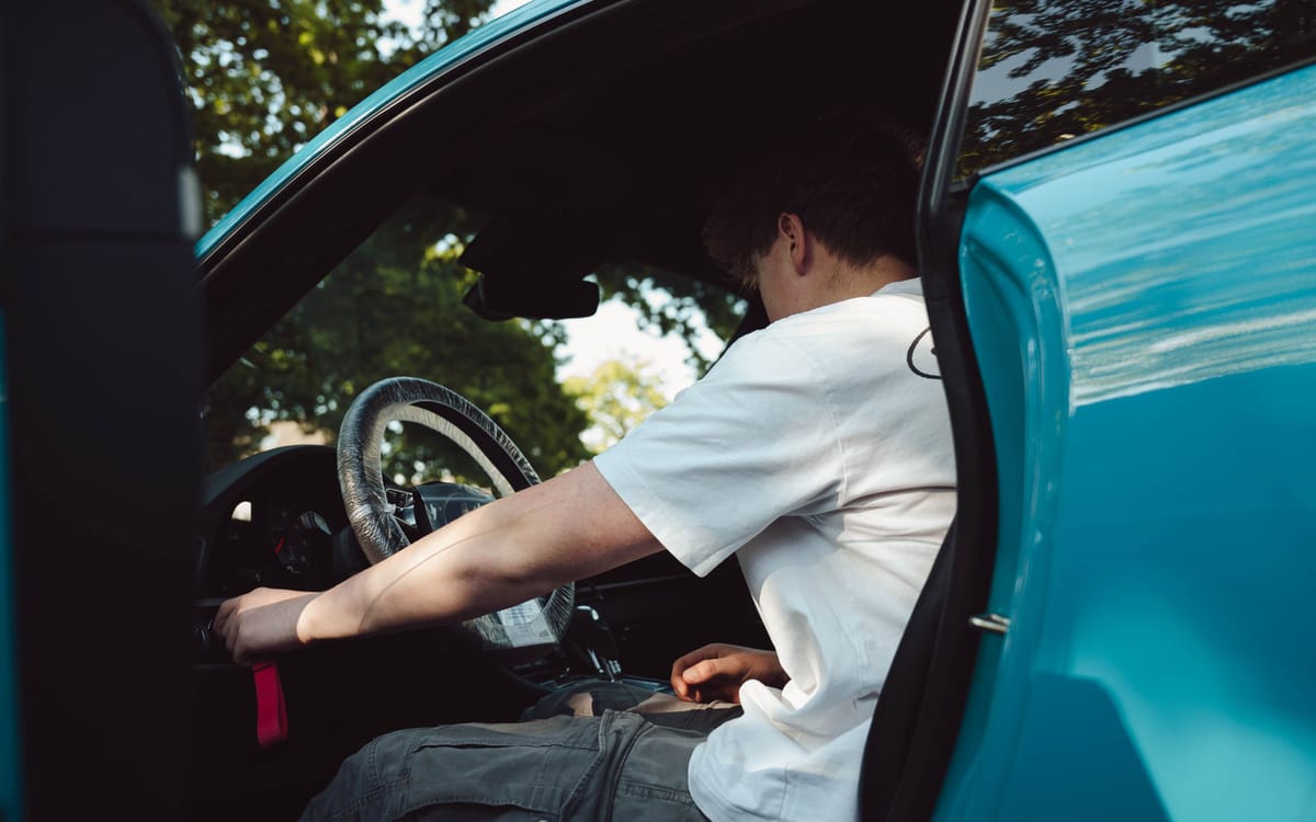 Ruben reinigt het interieur van een turquoise Porsche 911 met het portier open