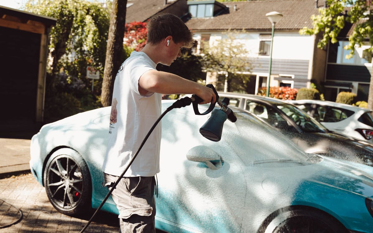 Ruben spuit snow foam over een turquoise Porsche 911 op straat
