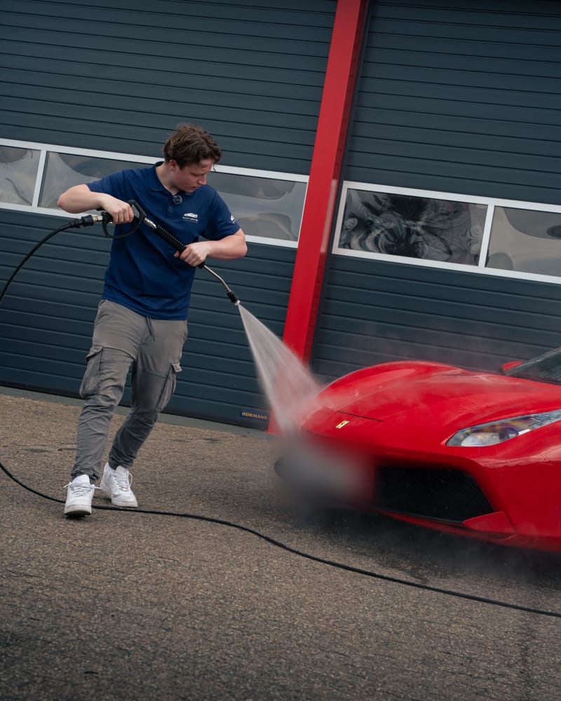 Ruben spoelt de voorkant van de Ferrari af met de hogedrukreiniger