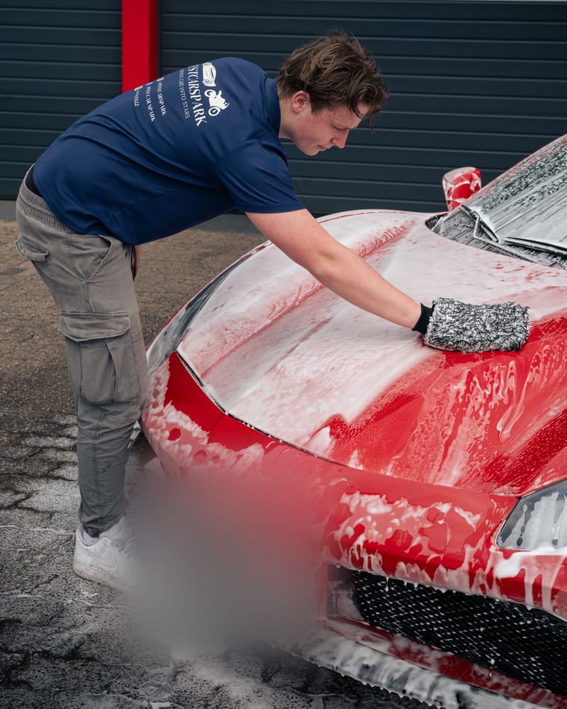 Ruben wast de ingeschuimde voorklep van de Ferrari met een washandschoen