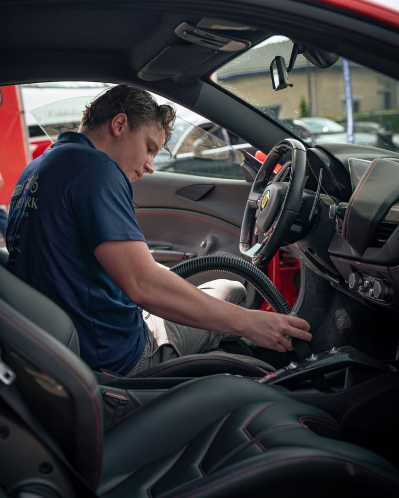 Ruben stofzuigt het interieur van de Ferrari bij de middenconsole